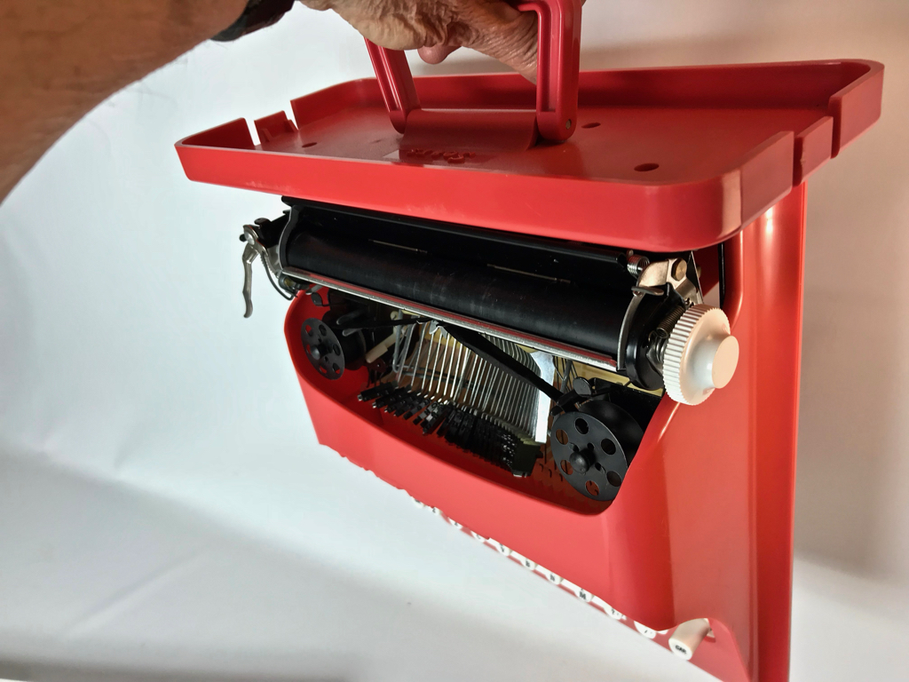 The case handle is attached to the typewriter frame, exactly like the Olivetti Valentine.